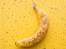 A ripe banana on a yellow background with spots - recipes for ripe and overripe bananas