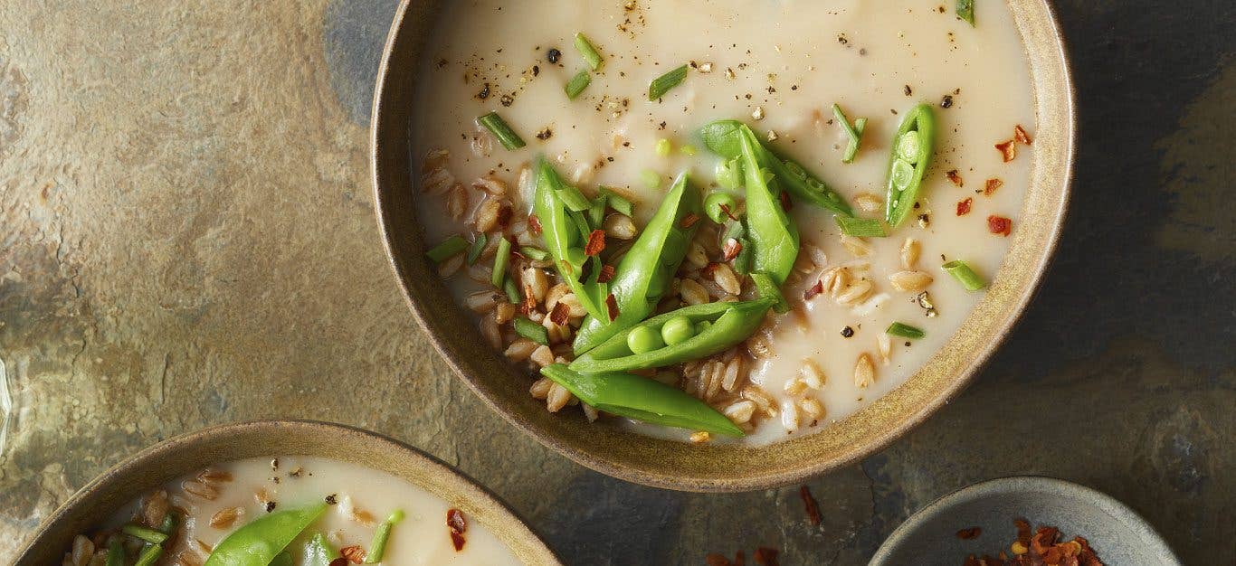 Caramelized Garlic and Potato Soup topped with snap peas in beige bowls