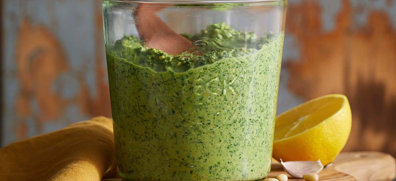 carrot top pesto in a glass jar next to a sliced lemon