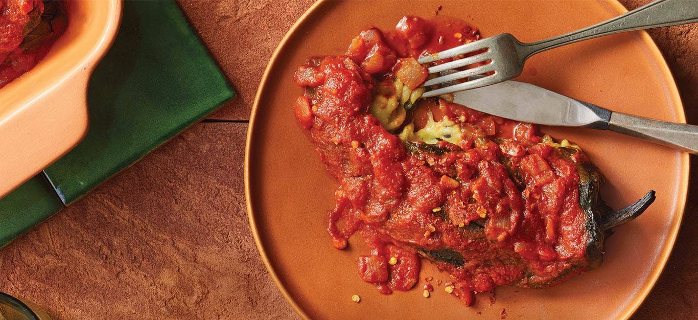 Vegan Chile Relleno on an orange plate with metal fork and knife