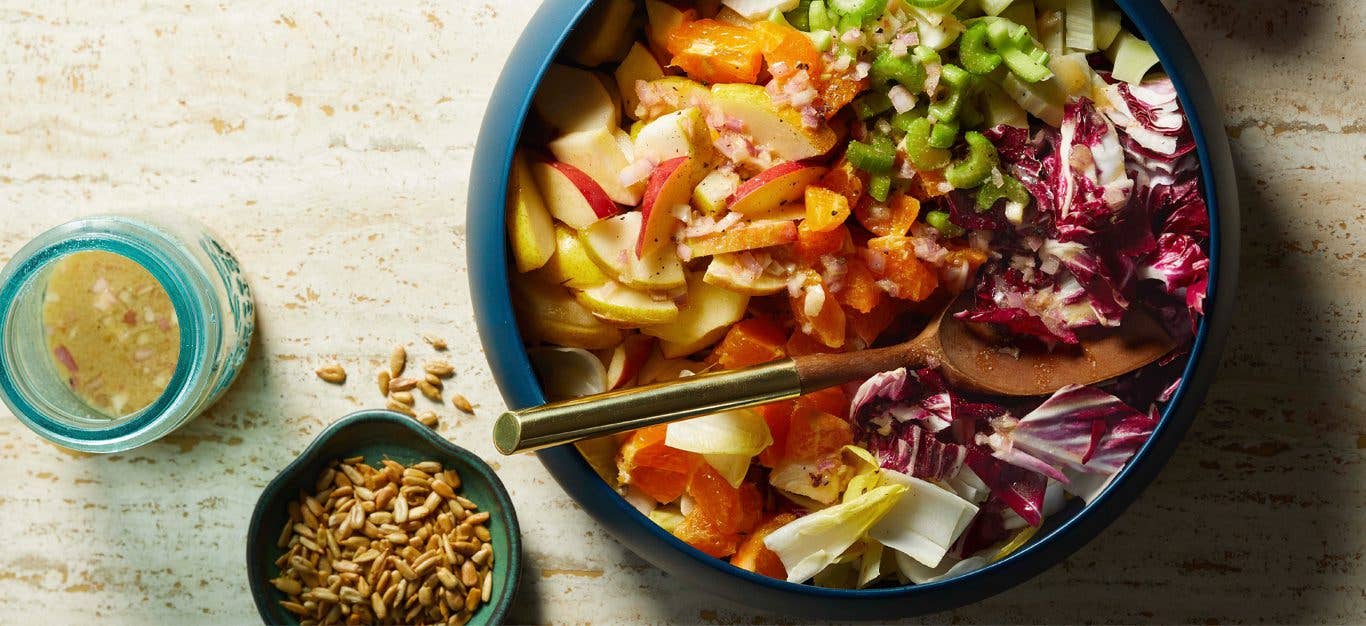 Chopped Winter Salad with Meyer Lemon Vinaigrette in a blue bowl with a serving spoon