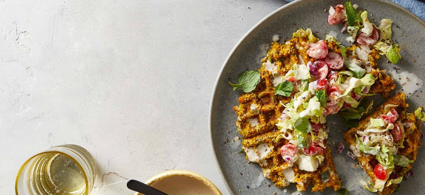 Falafel made in a waffle maker, topped with a tahini-dressed chopped salad