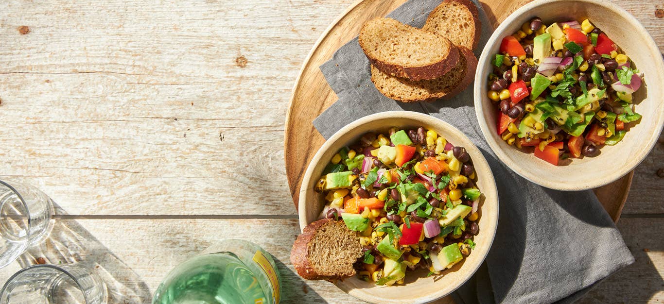 Grilled Corn Salad with Jalapeño Dressing in a cream colored bowl with a side of toasted bread slices