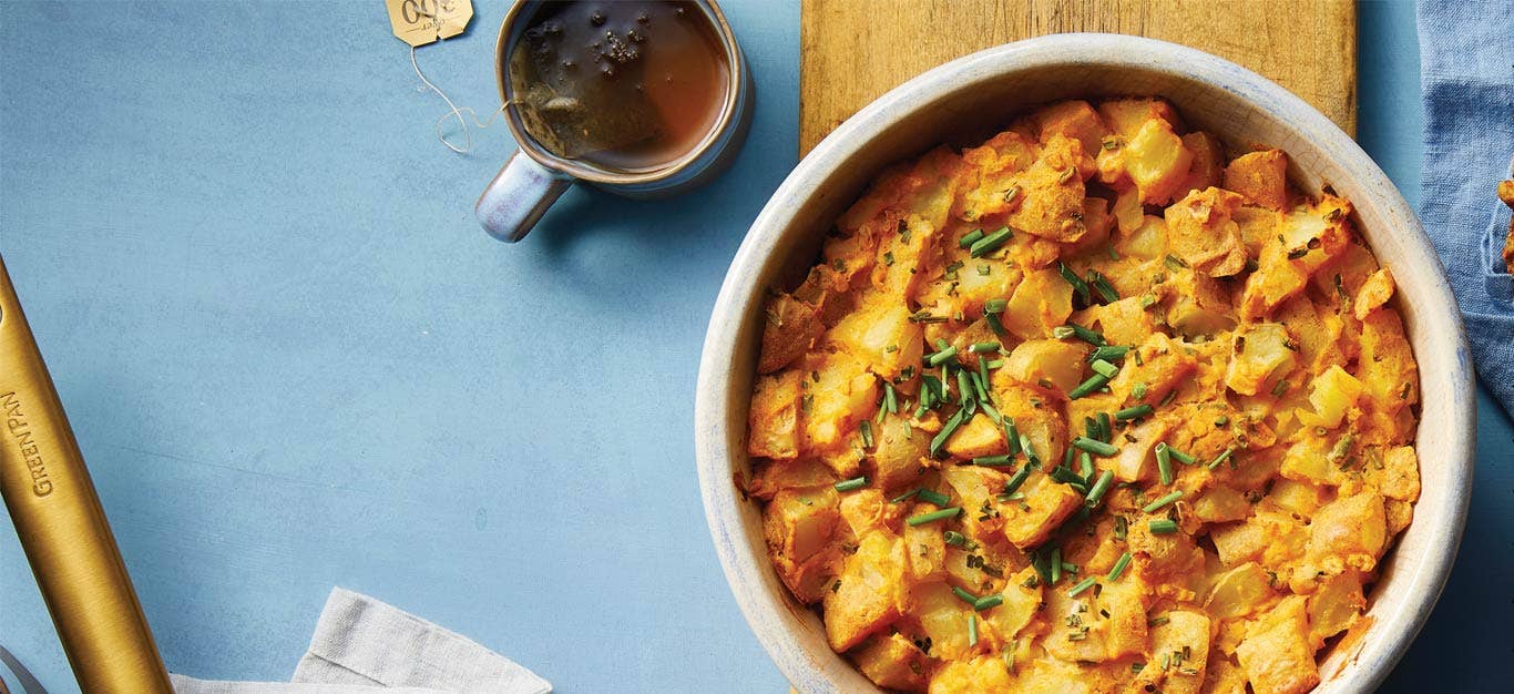 Cheesy Vegan Potato Casserole in a white bowl against a blue background