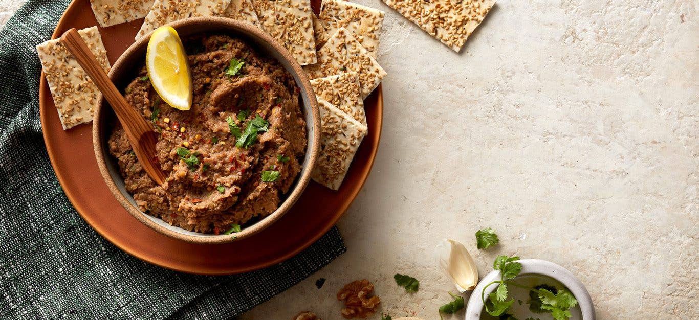 lentil-walnut vegan pate served with crackers and garnished with herbs