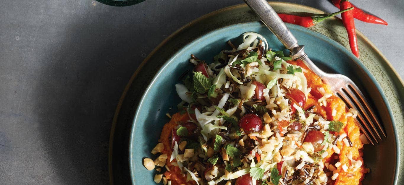 Spicy Thai Cabbage and Rice Salad with Sweet Potatoes in a blue ceramic bowl with a metal fork on a gray tabletop