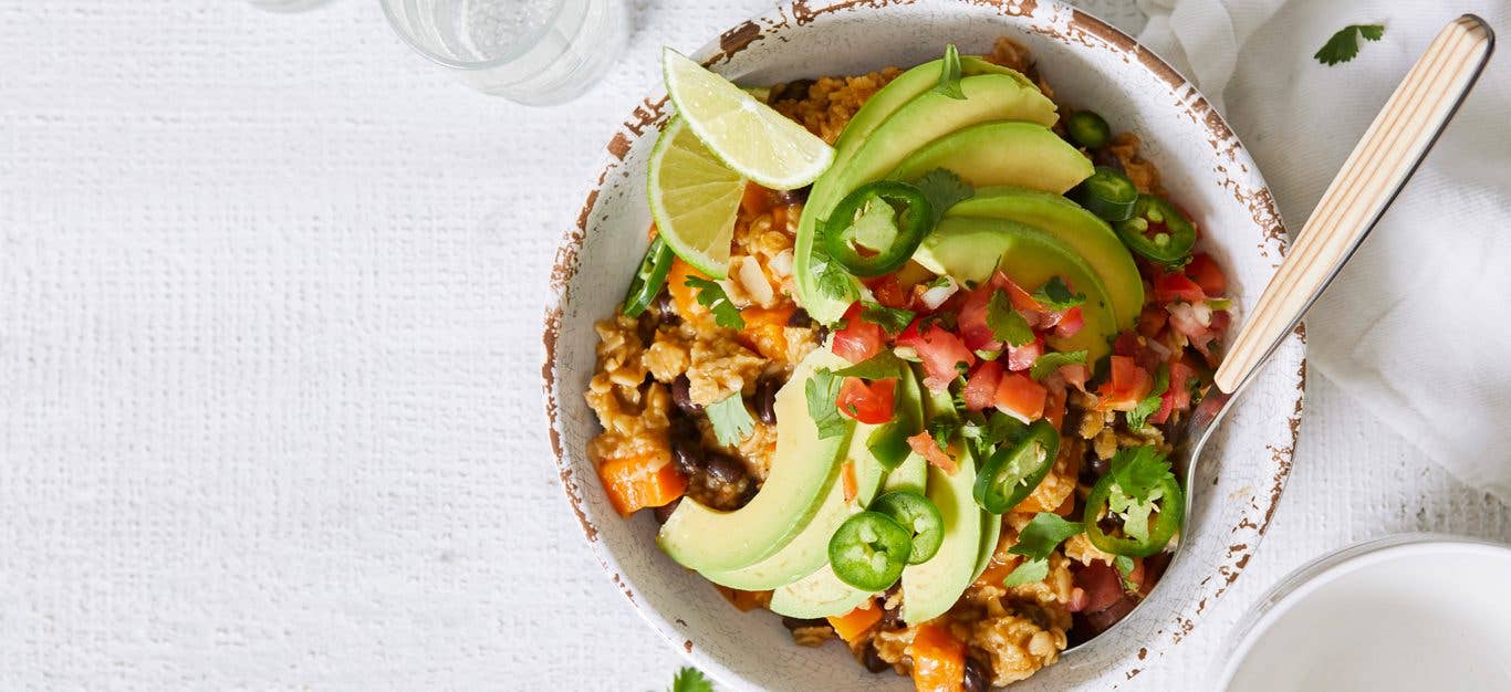 Southwestern Savory Oatmeal topped with avocado and salsa in a white bowl