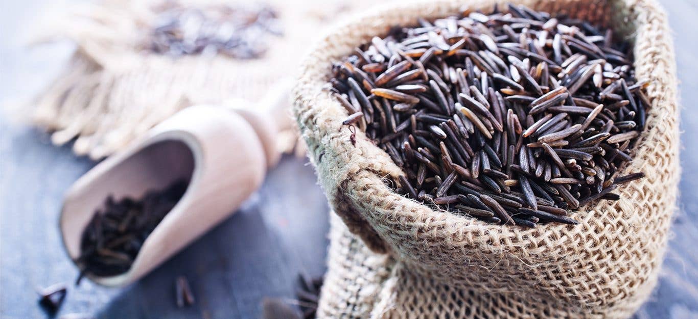 Wild rice in a bag and scoop on a wooden table